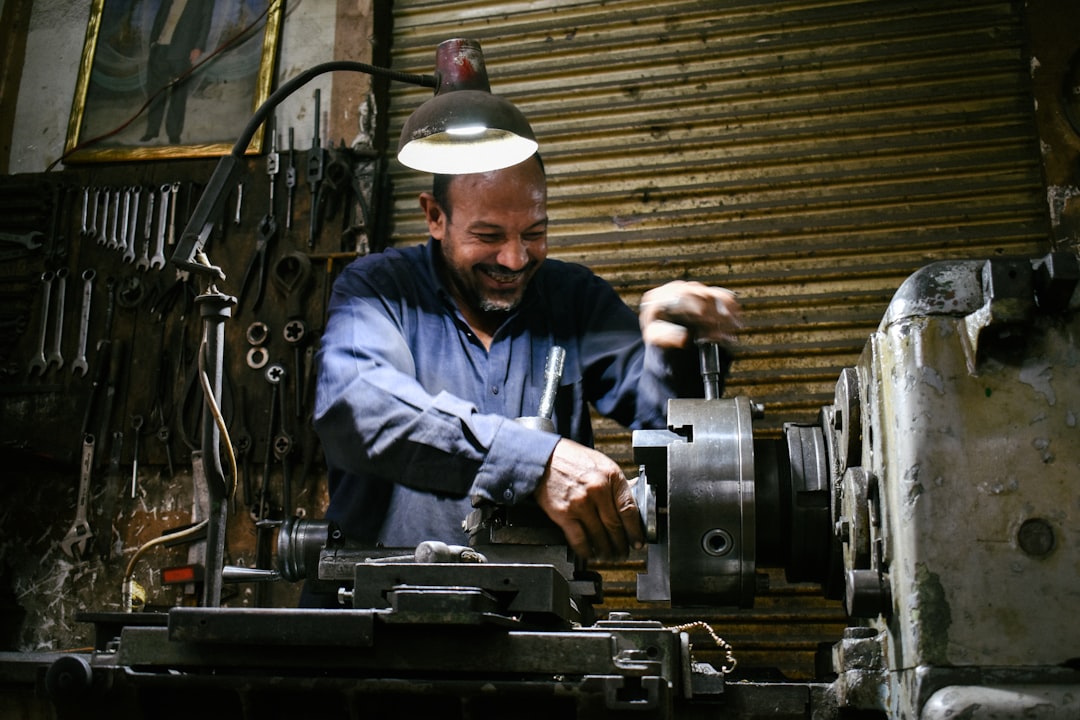 A smiling machinist works in a workshop.