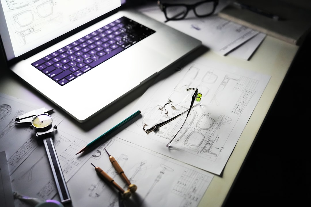 Desk with laptop, blueprints, and tools