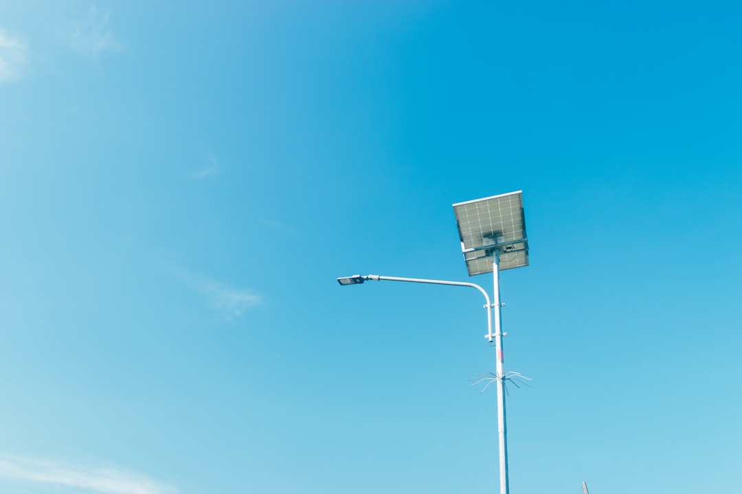 Street light with solar panel against blue sky.