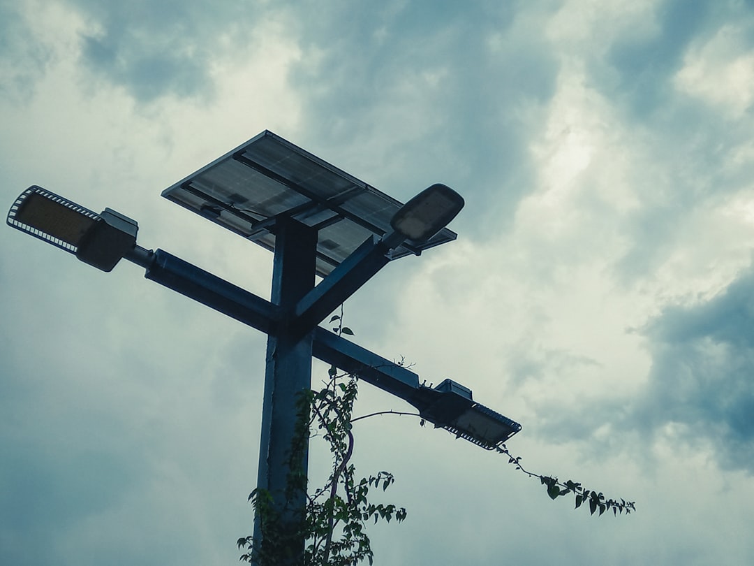 Solar-powered street light against a cloudy sky.