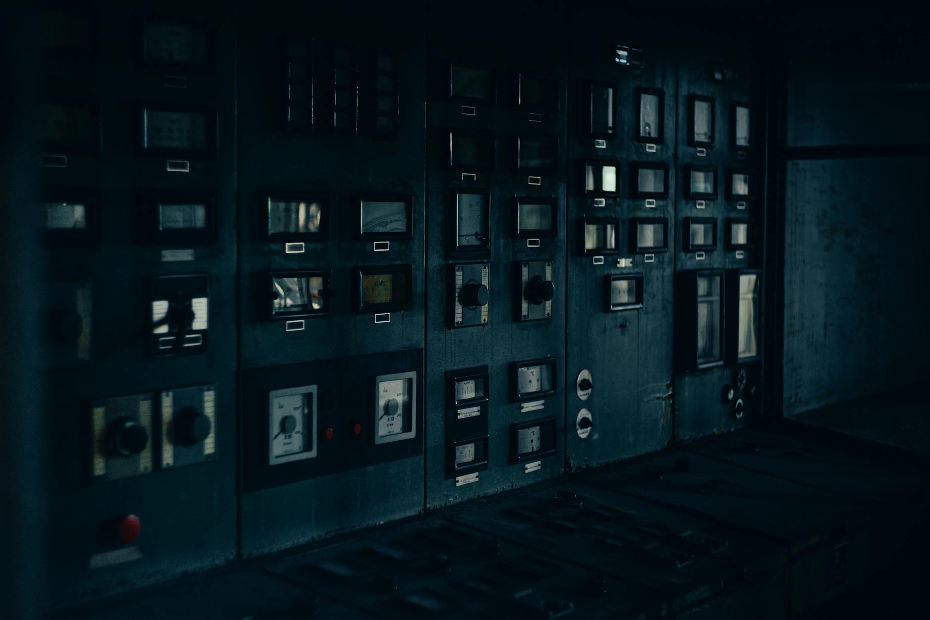 A dark, retro industrial control panel with dials and gauges in a maintenance room.