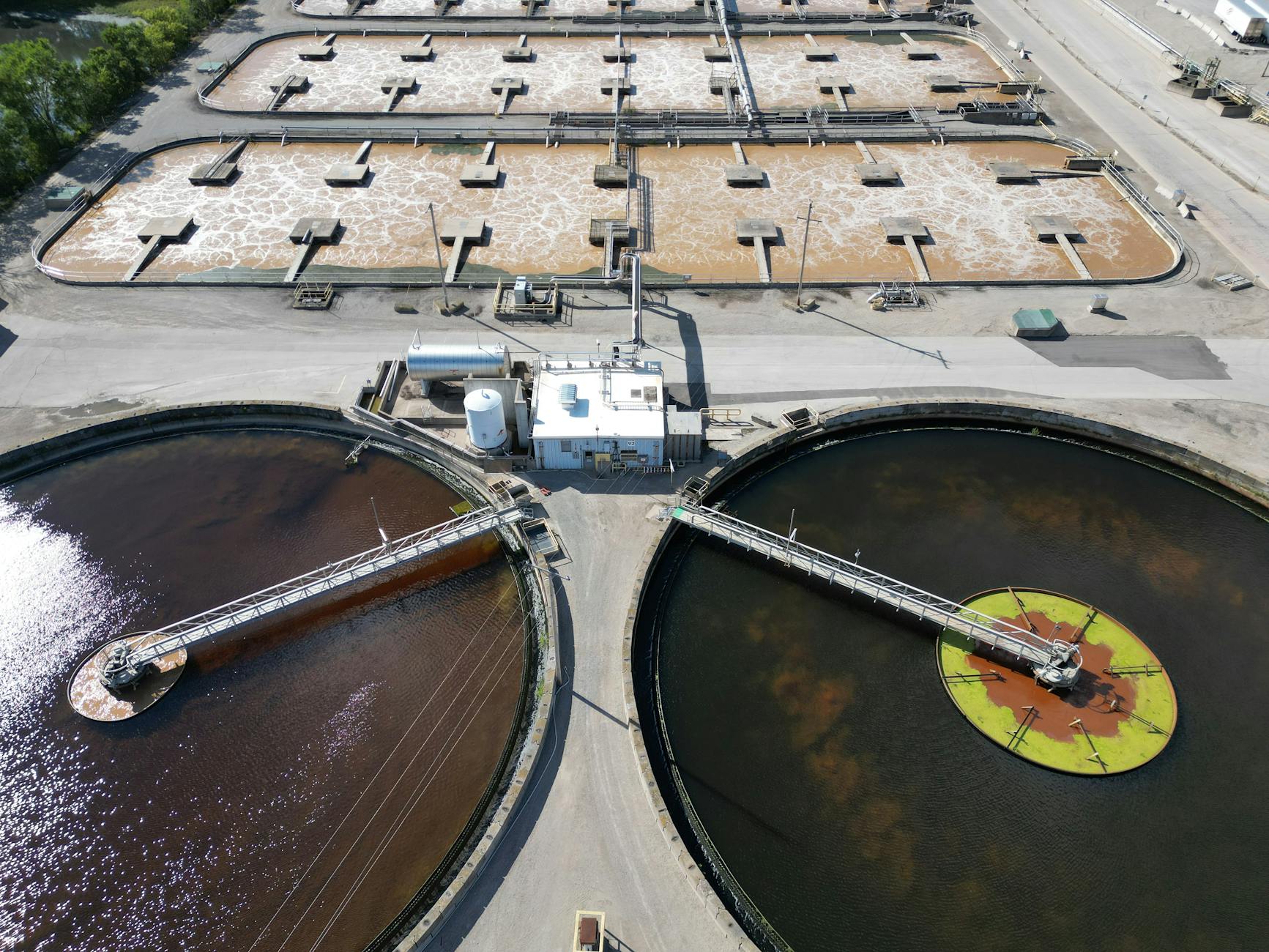Aerial shot of an industrial water treatment plant with large circular tanks.