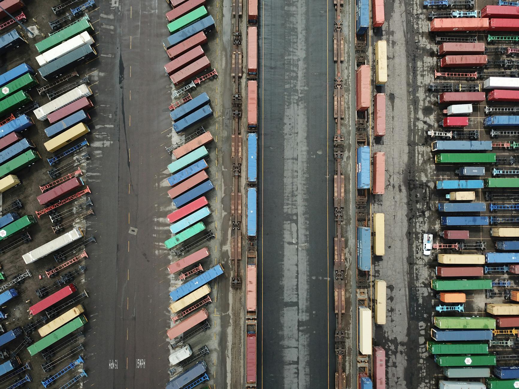Aerial shot of colorful shipping containers lined up at a busy port terminal.