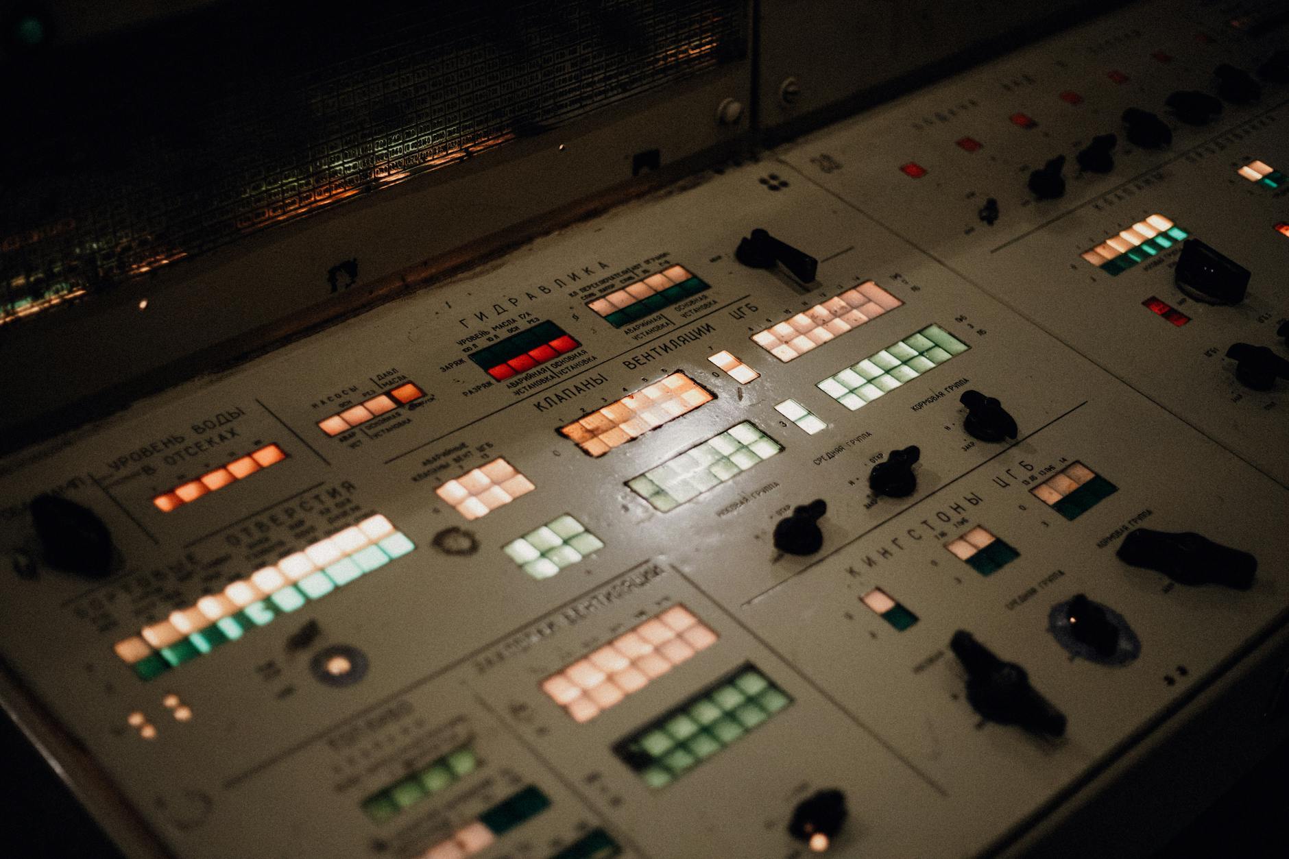 Close-up of an illuminated vintage control panel with various buttons and switches.