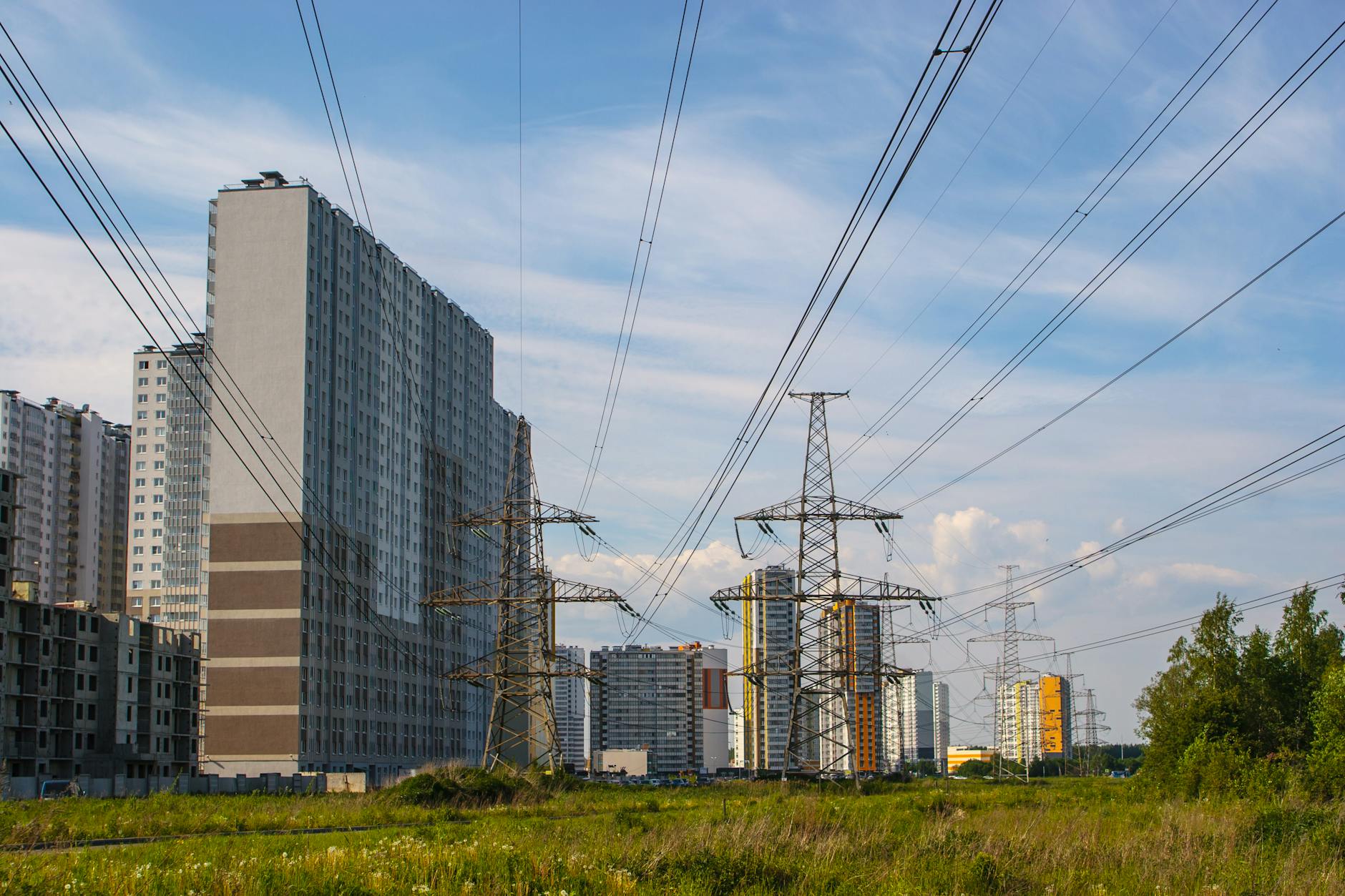 Urban scene showcasing apartment buildings and electricity towers under a clear sky.