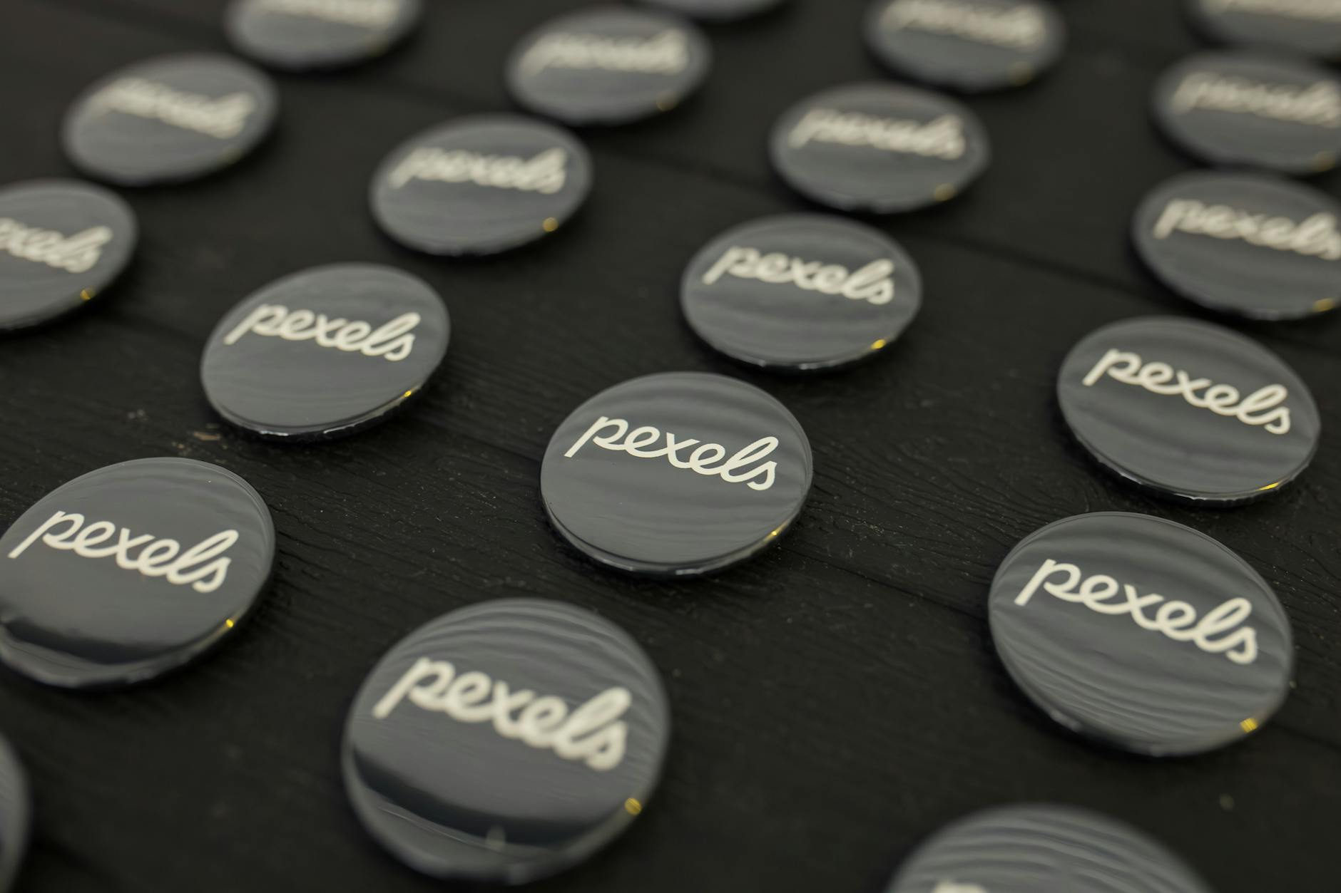 A close-up view of multiple Pexels logo buttons arranged neatly on a dark surface.