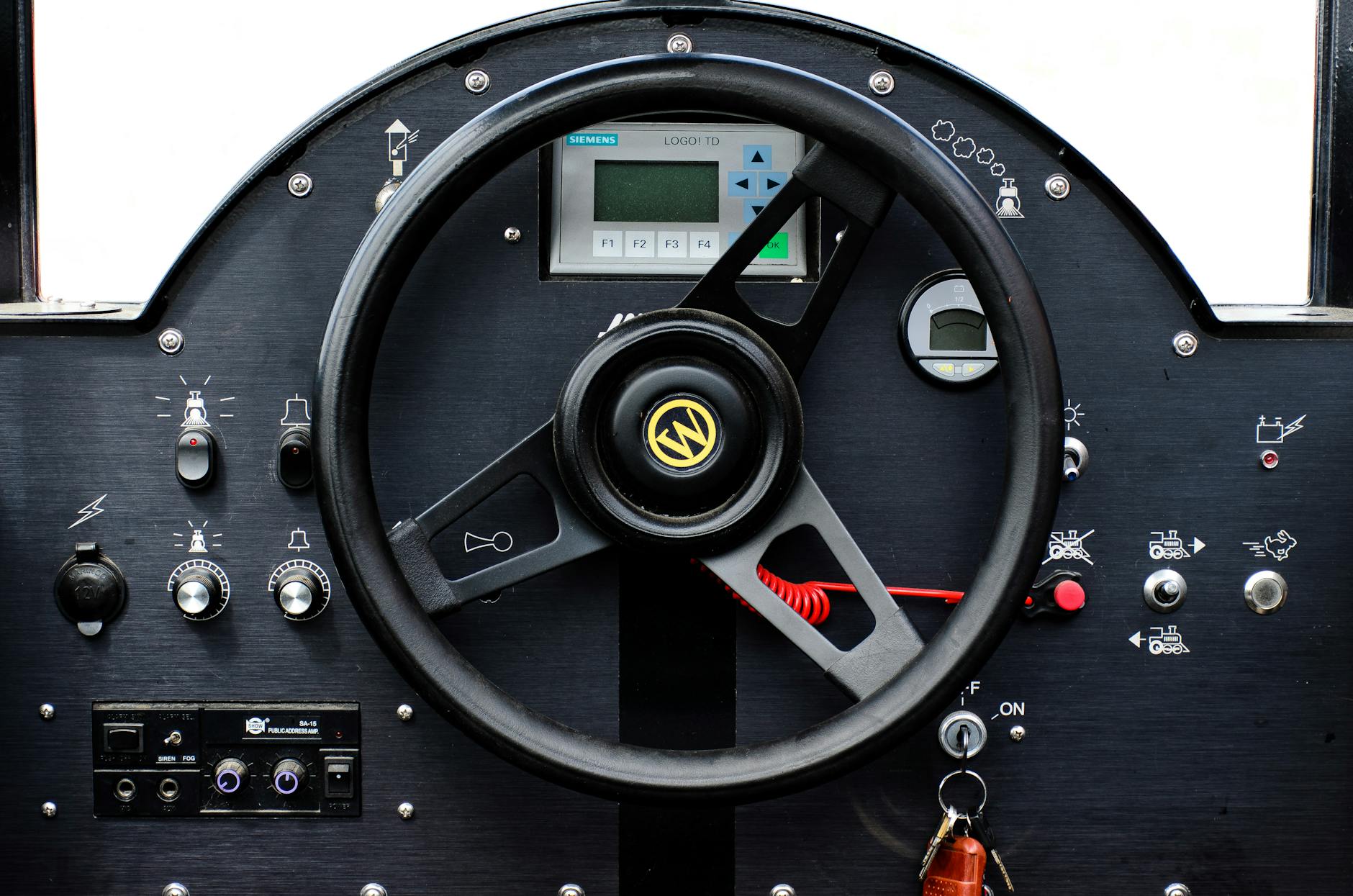 Close-up of an industrial control dashboard with various buttons and a steering wheel.