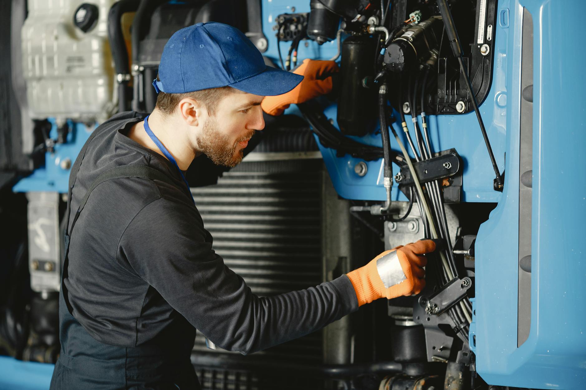 Skilled worker in safety gear repairing industrial equipment.